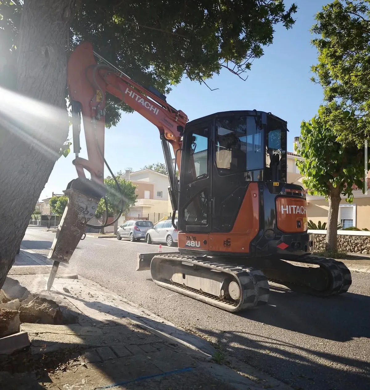 Miniexcavadora Hitachi con martillo hidráulico trabajando en zona urbana