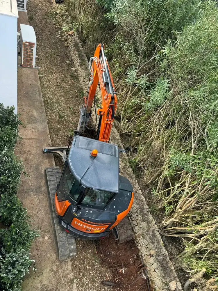 Miniexcavadora de Lorenzo Excavaciones trabajando entre la vegetación de una finca en Menorca