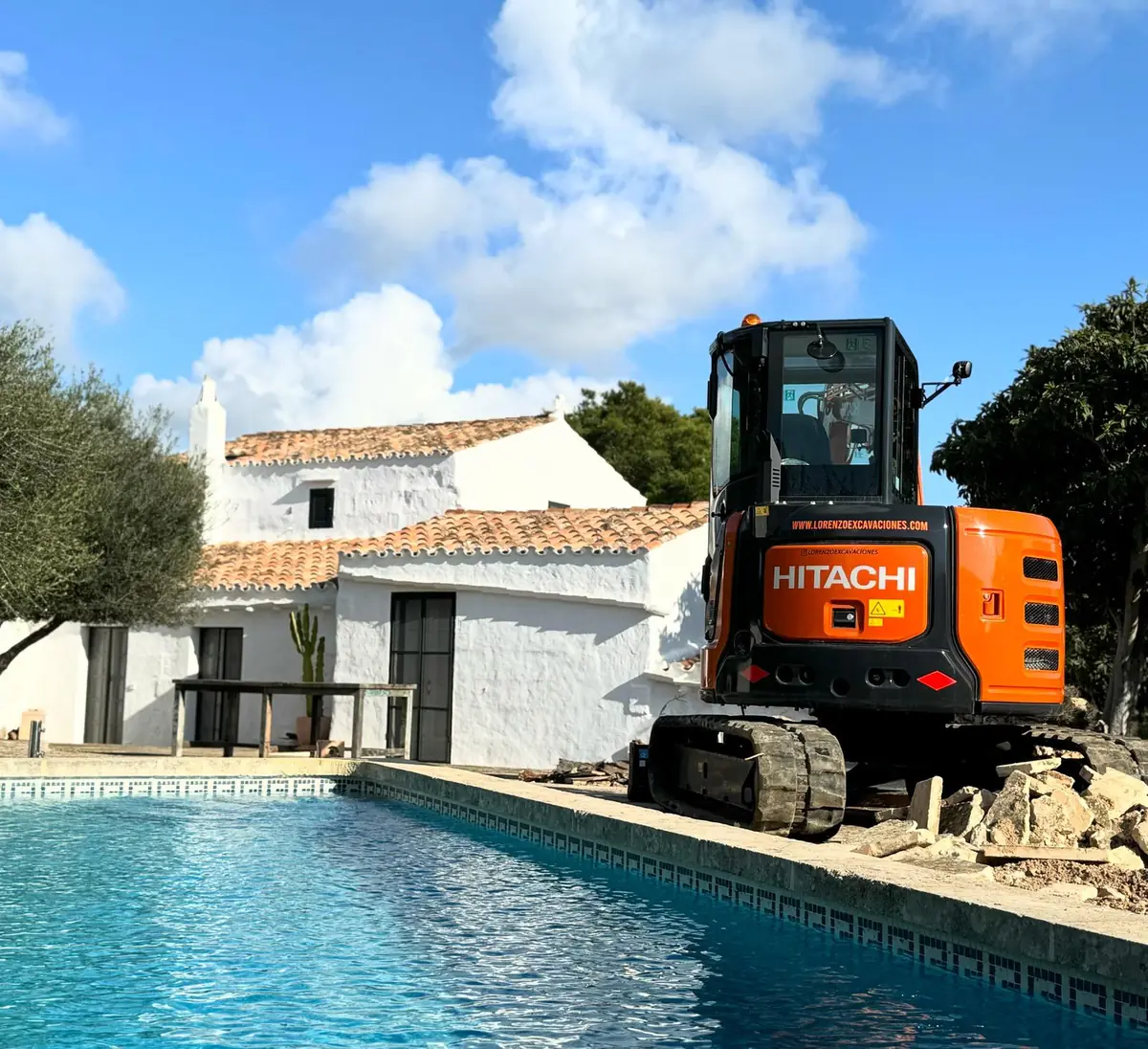 Miniexcavadora de Lorenzo Excavaciones trabajando al borde de una piscina