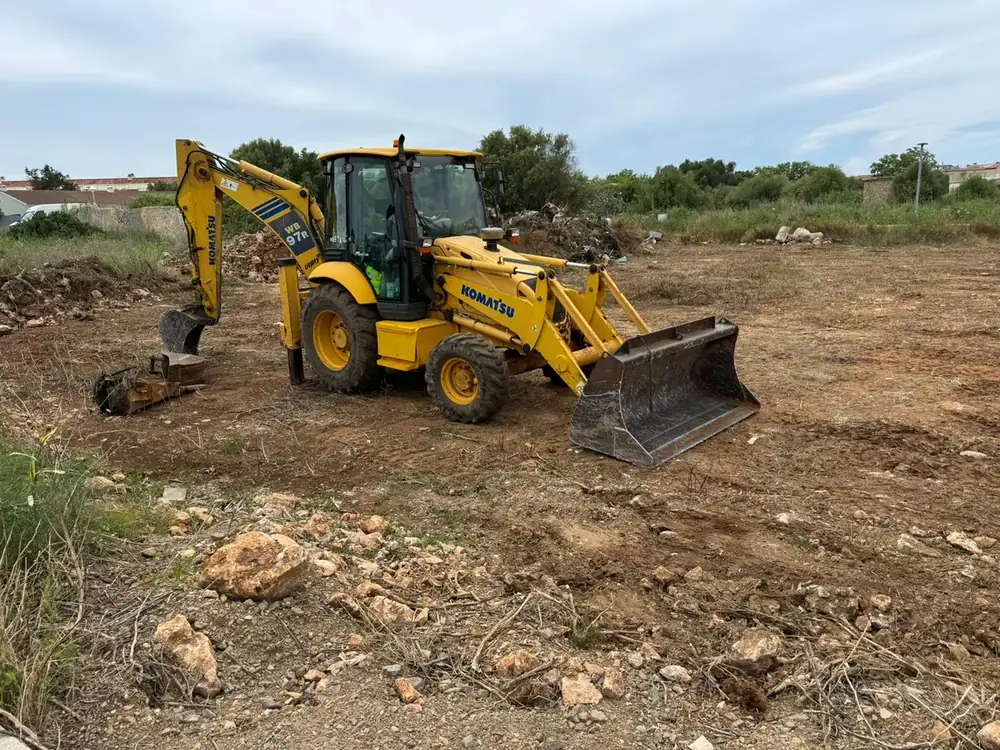 Retroexcavadora mixta Komatsu WB97R con pala frontal en una parcela